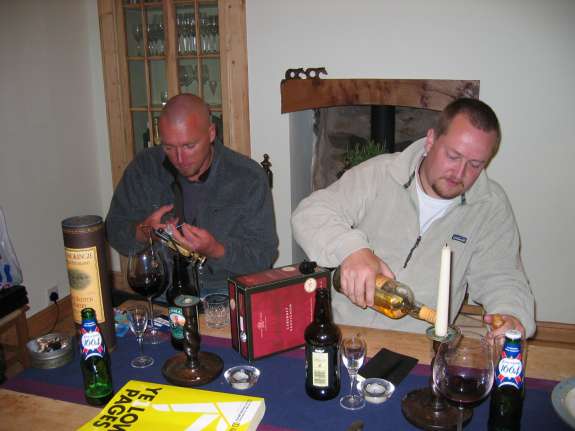 plunder11.jpg - The flytying begins... there does appear to be quite a lot of alcohol in this picture, but there were ten of us and so that's okay then. Here I'm tying a special little nymphet while Lars is busying himself with a toast to my flytying skills. Both Lars and Al (and all the other seven people in the room) were most impressed with my flytying skills and Lars said he may even write a book about it one day.You'll also notice the Yellow Pages, we'll be finding out what that's all about later, when Al writes about the trip.